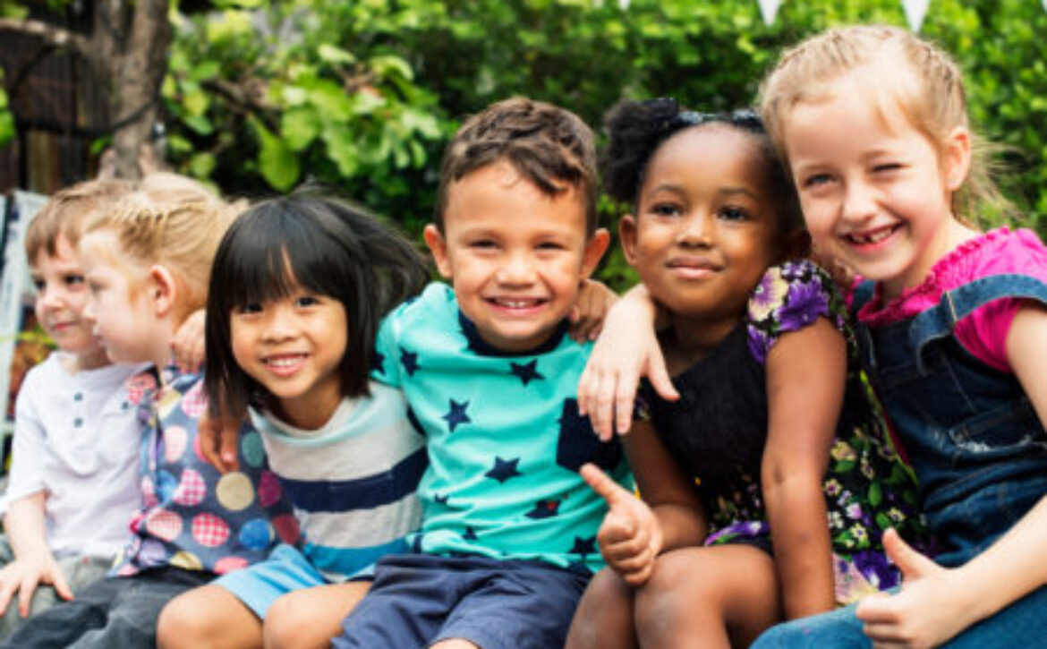Group of kindergarten kids friends arm around sitting and smilin