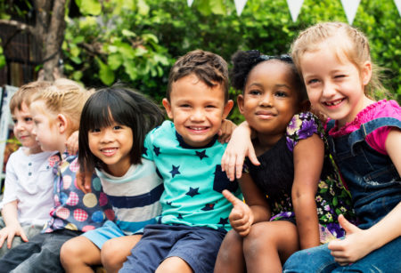 Group of kindergarten kids friends arm around sitting and smilin