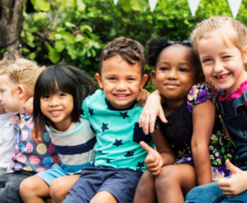 Group of kindergarten kids friends arm around sitting and smilin