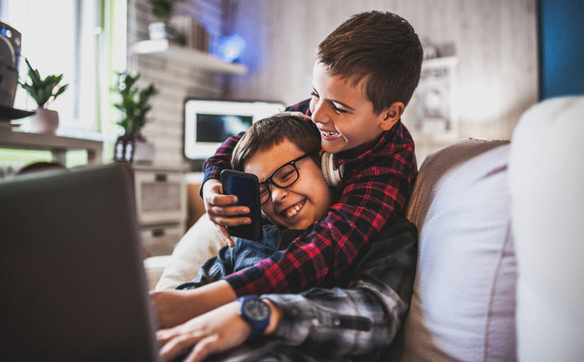 Two teenage boys with gadgets on couch at home