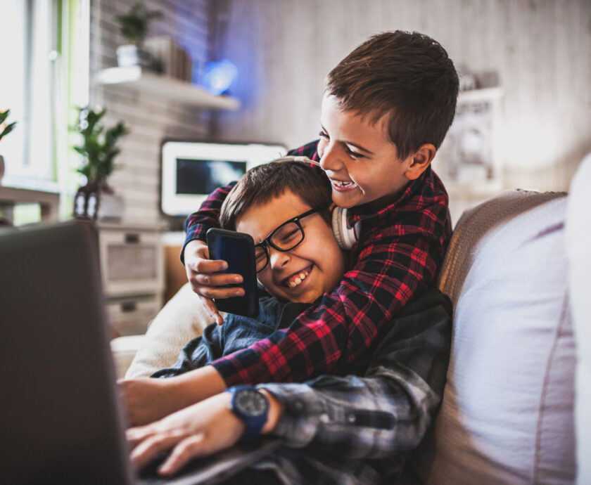 Two teenage boys with gadgets on couch at home